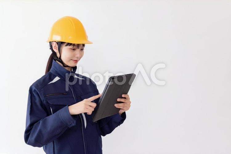 タブレットを使用する作業服の女性 女性,人物,日本人の写真素材