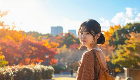 紅葉を背景に振り返る笑顔の若い女性 紅葉を背景に振り返る笑顔の若い女性の写真