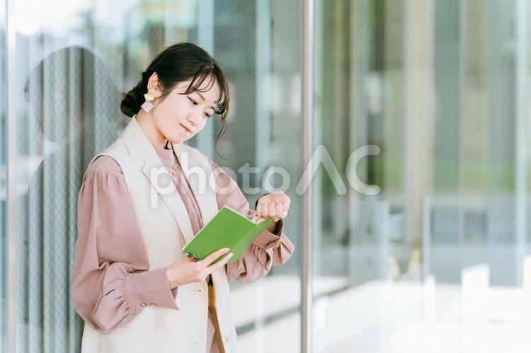 腕時計で時間を見て手帳を確認する女性 忙しい,多忙,疲労の写真素材