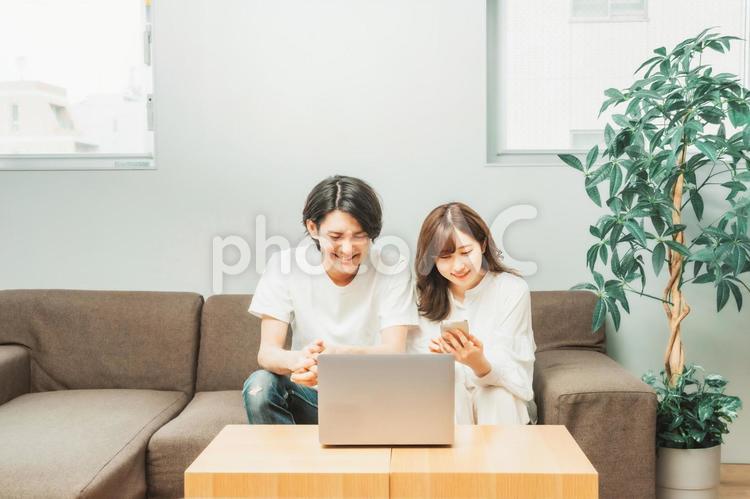 ノートパソコンとスマホを使う男女 ノートパソコン,スマホ,検索の写真素材