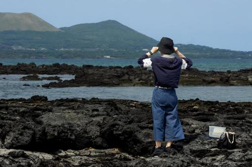 <素材>五島の海で一人鬼岳を眺める女性 <素材>五島の海で一人鬼岳を眺める女性 女性,人物,悩むの写真素材