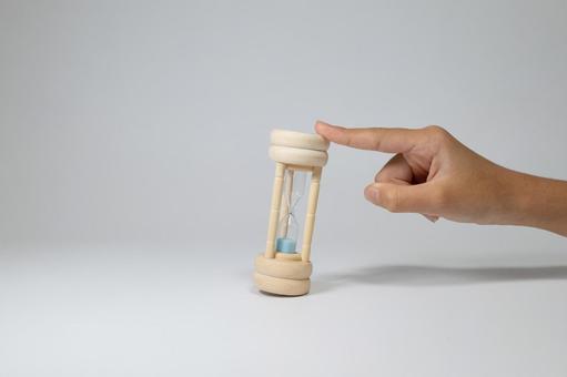 砂時計のてっぺんを指で軽く押さえる手 砂時計,時間,手の写真素材