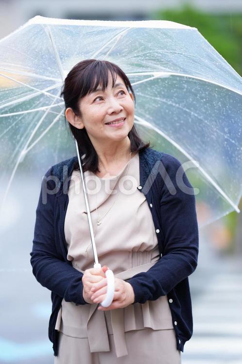 雨の中で空を見上げる女性 主婦,シニア,中年の写真素材