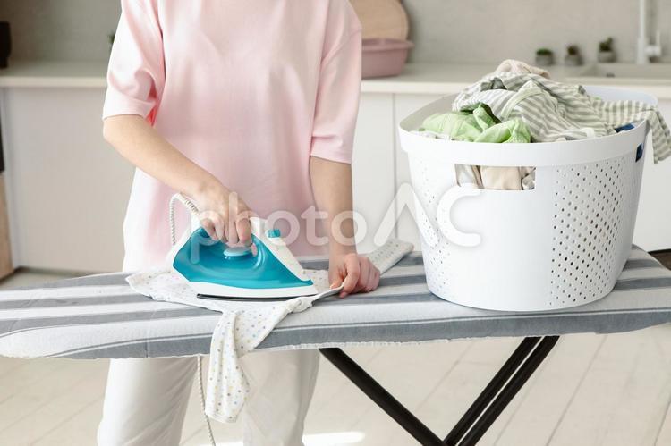 洗濯物の横でアイロンする女性 手元,立つ,洗濯物の写真素材