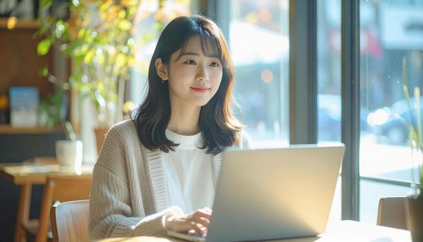 カフェでノートパソコンを使う日本人女性 カフェでノートパソコンを使う日本人女性の写真