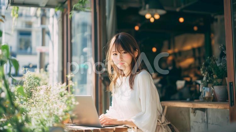 	緑豊かなカフェでノートPCを使用する女性 カフェ,女性,緑の写真素材