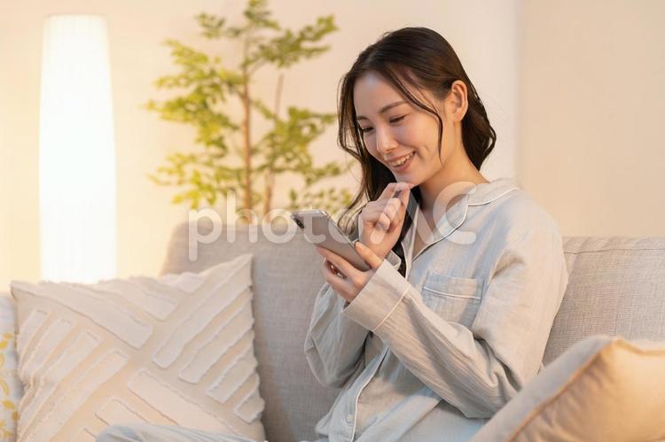 寝室で携帯を見る女性 女性,若い,夜の写真素材