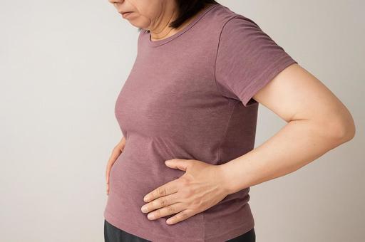 お腹を気にする女性 お腹を気にする女性の写真