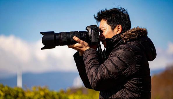 レンズを向ける日本人男性カメラマン レンズを向ける日本人男性カメラマンの写真