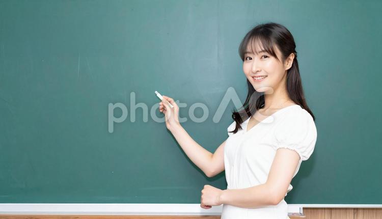 黒板に書こうとする先生 女性,ポーズ,教室の写真素材