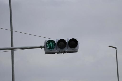 青色の点灯する信号機のアップの写真