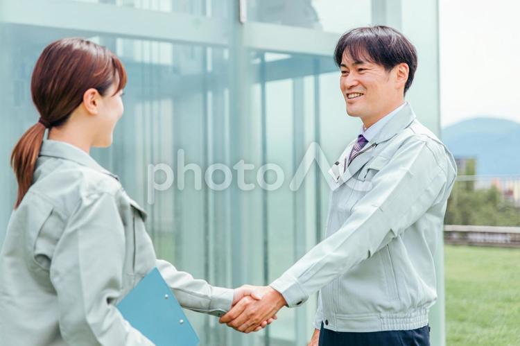 握手する作業着姿の男女（契約） 握手,契約,作業服の写真素材