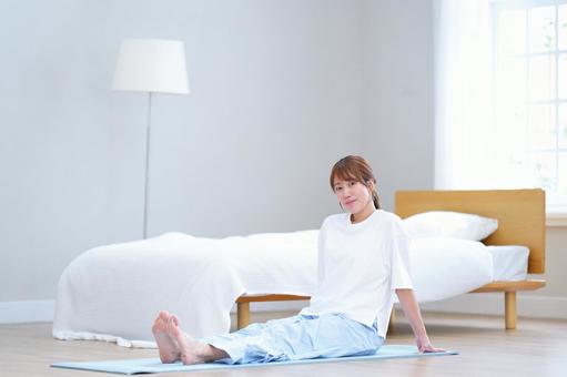 カメラ目線でヨガマットに座る女性の写真