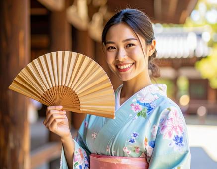 浴衣姿で扇子を持つ笑顔の女性の写真
