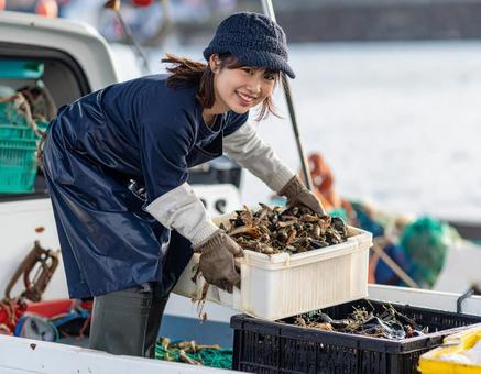 水揚げした魚介類を軽トラに積む漁師の女性 水揚げした魚介類を軽トラに積む漁師の女性の写真