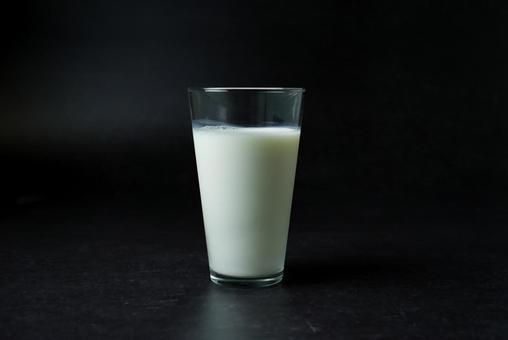 黒背景のコップに入った牛乳（横）の写真