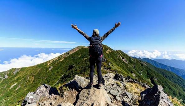 山登りで山頂で深呼吸する女性の後ろ姿 山登りで山頂で深呼吸する女性の後ろ姿の写真