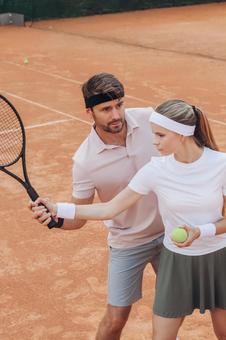 一緒にスイングの練習をする男女の写真