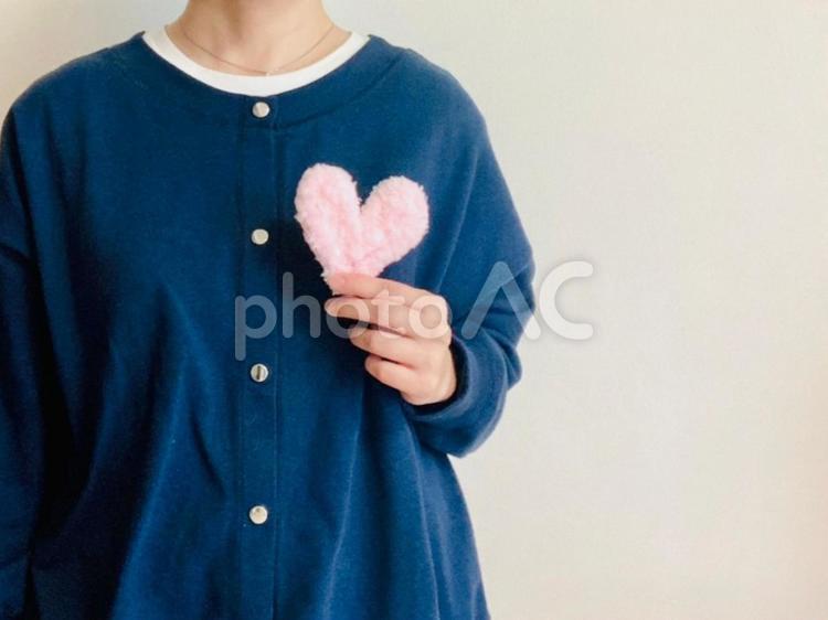 ピンクのハートを持つ女性（紺トップス） ハート,女性,ケアの写真素材