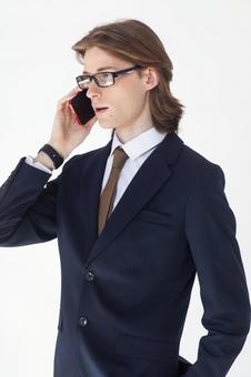 スマートフォンで電話しているスーツにメガネの男性 男性,外国人,欧米人の写真素材