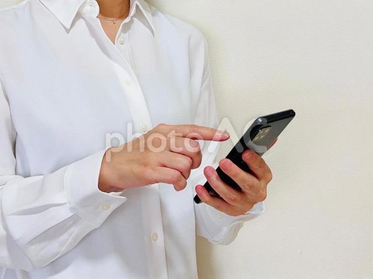 スマホをいじる白シャツを着た女性 スマホ,女性,携帯の写真素材
