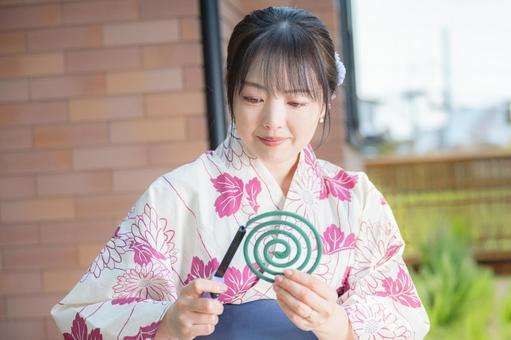 蚊取り線香に火をつける浴衣女性 蚊取り線香に火をつける浴衣女性 浴衣,女性,和装の写真素材