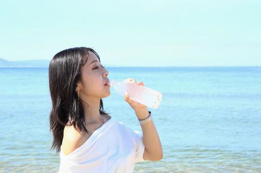 海辺で水を飲む女性 海辺で水を飲む女性 女性,海,夏の写真素材