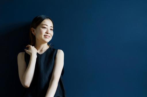 藍色の壁の部屋でリラックスした表情の女性  ポートレート,女性,黒髪の写真素材