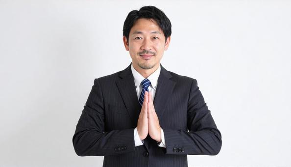両手をあわせてお願いしているビジネスマン 両手をあわせてお願いしているビジネスマンの写真
