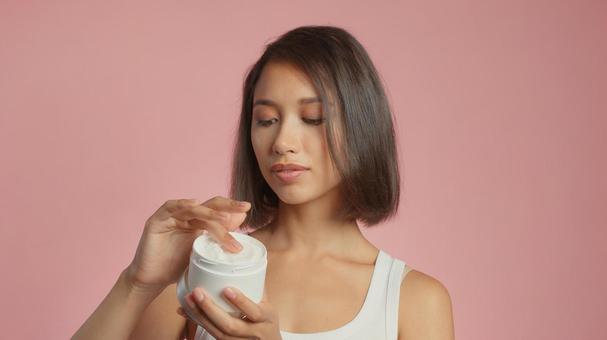 クリームを容器からすくっている女性 クリームを容器からすくっている女性 女性,外国人,アジア人の写真素材