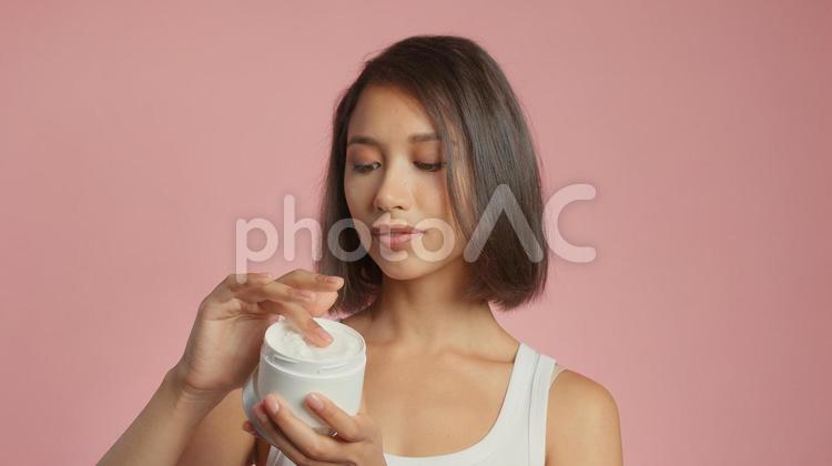 クリームを容器からすくっている女性 女性,外国人,アジア人の写真素材