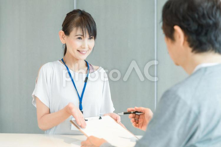 スポーツジムの受付をする女性（記入） スポーツジム,受付,スタッフの写真素材