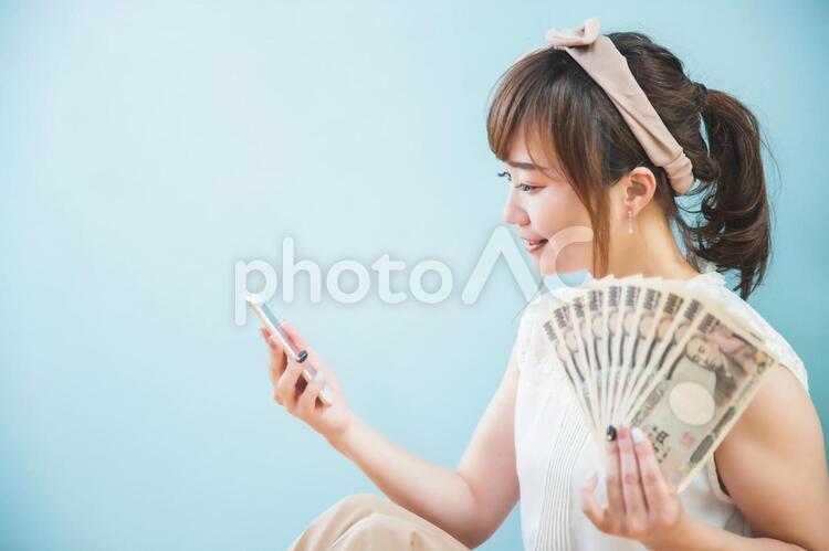 スマホとお金を持つ女性 副業,サイドビジネス,副収入の写真素材