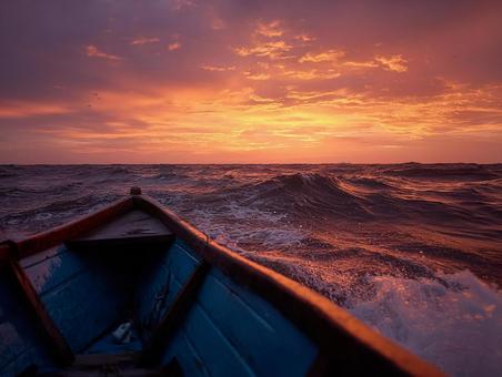 夕日に向かって進む小さな船の写真