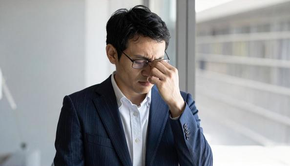 目を手で押さえて苦しむ日本人ビジネスマン 目を手で押さえて苦しむ日本人ビジネスマンの写真