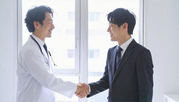 握手するビジネスパーソンと医者 握手するビジネスパーソンと医者の写真