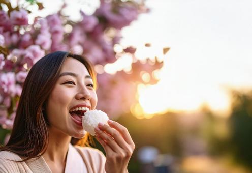 花見でおにぎりを食べる若い女性 花見でおにぎりを食べる若い女性の写真