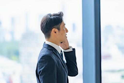 高層ビルで電話をするビジネスマン 高層ビルで電話をするビジネスマン ビジネスマン,男性,スーツの写真素材