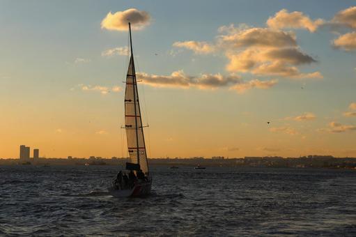 夕暮れの海峡を渡るヨットの写真