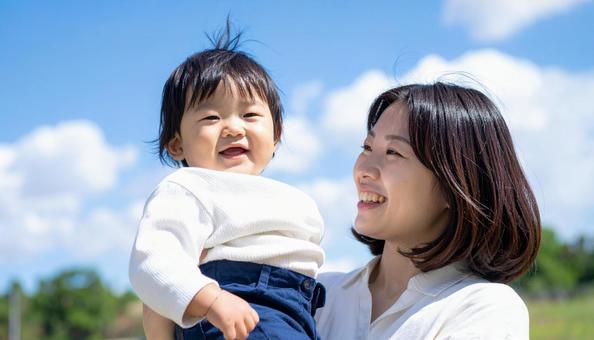青空の下、子供を抱っこする母親 青空の下、子供を抱っこする母親の写真