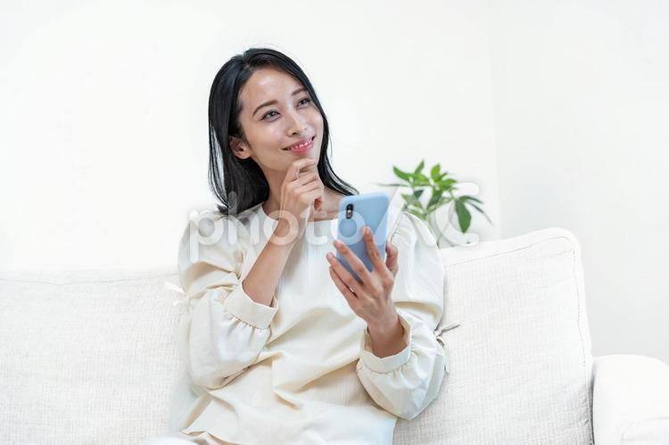 携帯を持ち考える日本人女性 スマホ,検索,アプリの写真素材