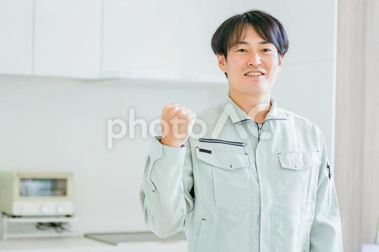キッチンと作業着姿の男性（カメラ目線） 工務店,作業服,設備の写真素材