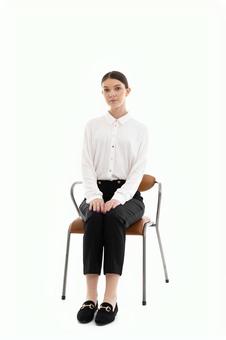 真顔で椅子に座るカメラ目線の女性 真顔で椅子に座るカメラ目線の女性の写真
