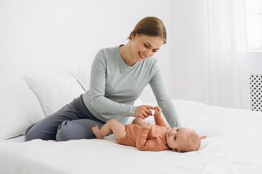 赤ちゃんに指を握られ嬉しい母親 赤ちゃんに指を握られ嬉しい母親 親子,仰向け,ベッドの写真素材