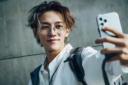 Portrait of a man taking a selfie with his smartphone, glasses, young, japanese, JPG
