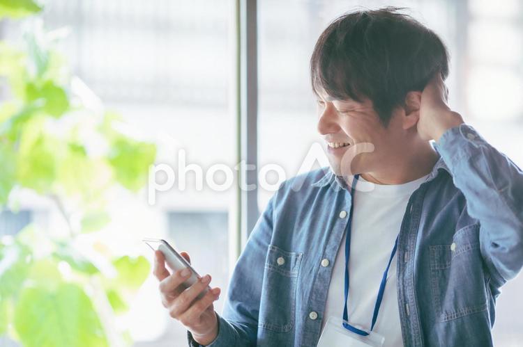 服装自由な会社でスマホを使う会社員 スマホ,検索,スマートフォンの写真素材