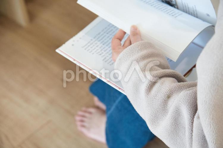 自宅で腰掛けて英文の本を読んでいる女性 本,読書,手元の写真素材