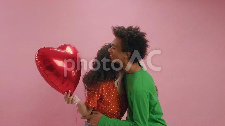 ハートのバルーンを持つ女性を抱く男性 男女,抱き合う,ハートの写真素材