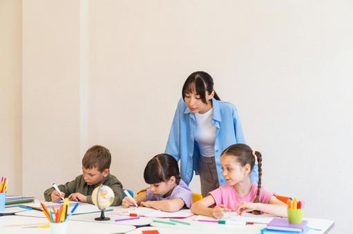 子どもたちのお絵描きを後ろから見守る先生 女性,女の子,男の子の写真素材
