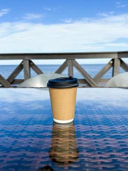 海辺のテラスに置かれたコーヒーカップ コーヒー,テイクアウト,紙コップの写真素材